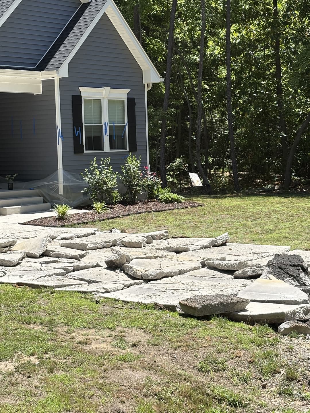 Stone pathway leading to a gray home with solar panels and landscaped garden.