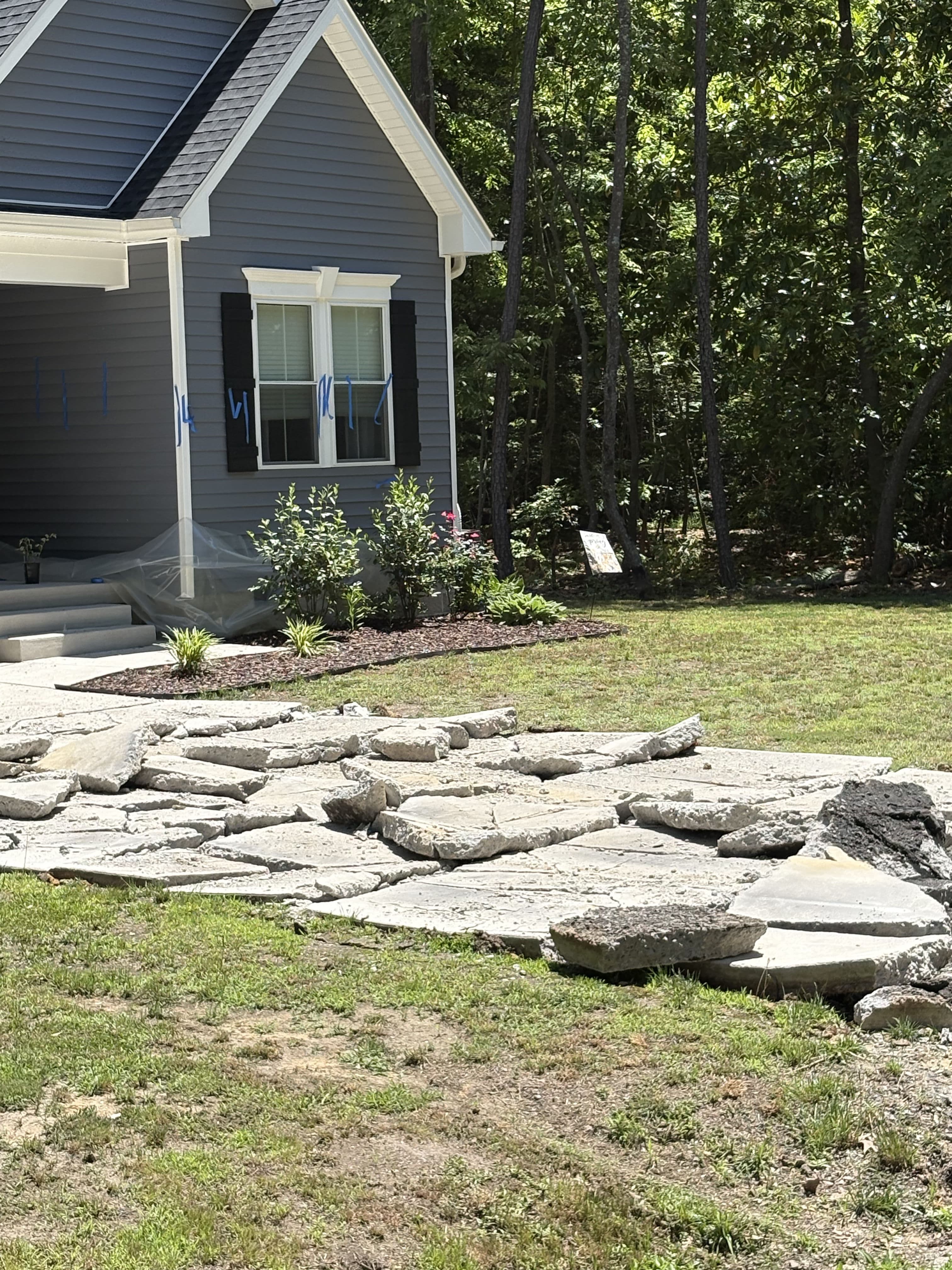 Stone pathway leading to a gray home with solar panels and landscaped garden.